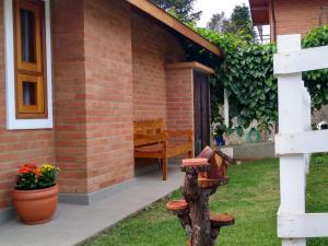 a brick house with a bench in the yard at Chalé Cantinho do Vovô in Monte Verde