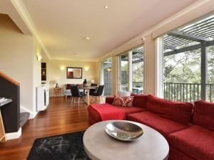 uma sala de estar com um sofá vermelho e uma mesa em Villa 2br Moscato Villa located within Cypress Lakes Resort em Pokolbin