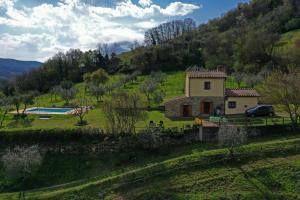 a house on a hill with a car parked in a field at Villa San Regolino whit private pool in Radicondoli