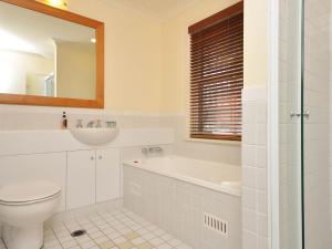 a white bathroom with a toilet and a sink at Villa 2br Petit Verdot Villa located within Cypress Lakes Resort in Pokolbin