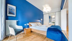 ein blaues Schlafzimmer mit einem Bett und einem Stuhl in der Unterkunft Apartamenty Sun & Snow Casa Marina in Świnoujście
