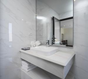 a white bathroom with a sink and a mirror at Boston Halong Hotel in Ha Long