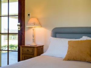 a bedroom with a bed with a lamp on a night stand at Roscrea Homestead - Premier Homestead Accommodation in Glenwilliam