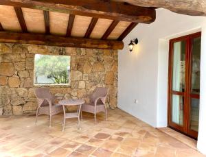 Un patio con mesa y sillas y un muro de piedra. en Punta D'Acu Country Resort, en Arzachena