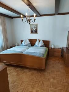 ein Schlafzimmer mit einem großen Holzbett mit einem Kronleuchter in der Unterkunft Ferienhaus und Ferienappartements Brunner in Höchst