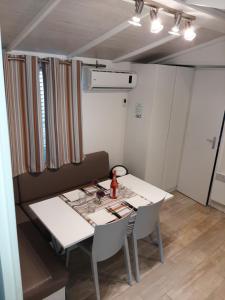 a dining room with a white table and chairs at Mobilhome dans Camping les Sables d'or in Cap d'Agde