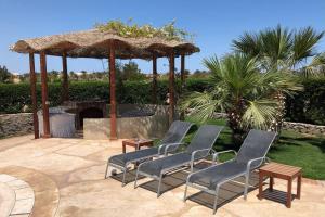 eine Gruppe Stühle und ein Sonnenschirm auf einer Terrasse in der Unterkunft Villa with 5 bedrooms & 4 bathrooms - private heated pool in Hurghada