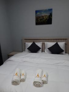 Una cama blanca con tres pares de zapatillas. en Paris Furnished Apartments - Tabasum Group, en Ajman