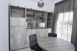 a kitchen with a wooden table and chairs and a sink at GERANI apartments in Órmos