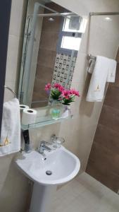 a bathroom with a sink and a mirror and pink flowers at Paris Furnished Apartments - Tabasum Group in Ajman 