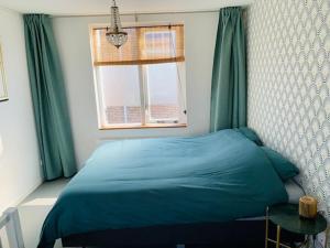 sypialnia z niebieskim łóżkiem i oknem w obiekcie King almost by the sea w Zandvoort