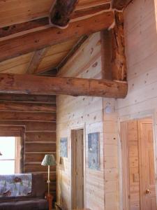 Habitación con paredes de madera y techo con vigas. en Renegade Log Cabin, en Custer