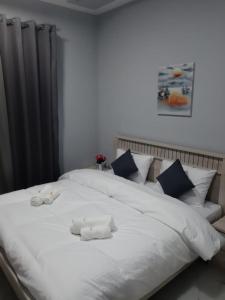a large white bed with two towels on it at Paris Furnished Apartments - Tabasum Group in Ajman 