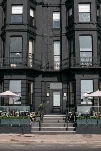 a building with tables and umbrellas in front of it at Port Hotel in Eastbourne