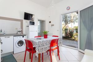 une cuisine avec une table et des chaises rouges ainsi qu'un lave-linge. dans l'établissement Nicola House Il Faro, à Cervia