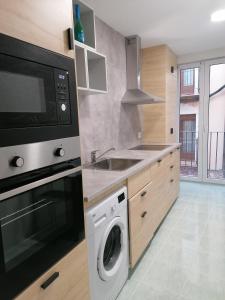 een keuken met een wasmachine en een magnetron bij Apartamentos El Cid in Molina de Aragón