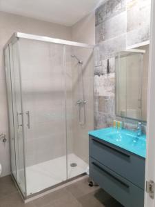 y baño con ducha y lavamanos azul. en Apartamentos El Cid, en Molina de Aragón