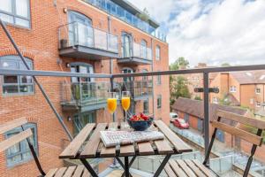 een balkon met een houten tafel en 2 glazen wijn bij Modern and chic city centre apartment with parking in Oxford