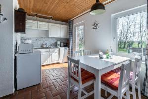 eine Küche mit einem weißen Tisch und Stühlen in einem Zimmer in der Unterkunft Deichgraf 2 in Friedrichskoog