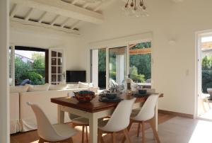 a dining room with a wooden table and white chairs at Maison sous les Pins in Cavalaire-sur-Mer
