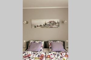 a bed with purple pillows and a picture on the wall at Modern apartment in Tarnow in Tarnów