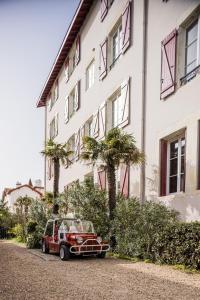 une voiture rouge garée devant un bâtiment dans l'établissement Hotel Saint Julien, à Biarritz