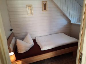 een klein bed met witte lakens en kussens in een kamer bij Ferienhaus Silke - östlich der Dorfstraße in Grieben Insel Hiddensee in Grieben