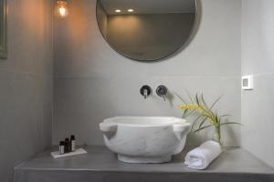 La salle de bains est pourvue d'un lavabo blanc et d'un miroir. dans l'établissement Oia Kissiri - private pool villas, à Oia