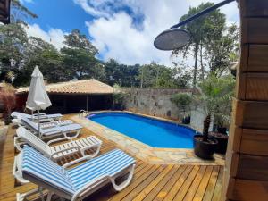 a swimming pool with lounge chairs on a wooden deck at Maré Leve Maresias in Maresias