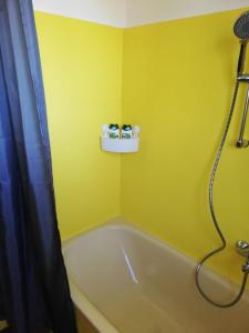 a yellow bathroom with a tub and a shower at Apartment Graz Lustbuhel in Graz