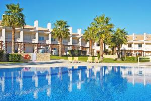 a swimming pool in front of a building with palm trees at Townhouse Mar 2 - Moradia com BBQ e vista mar - Albufeira in Albufeira