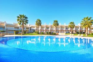 a large swimming pool in front of a building with palm trees at Townhouse Mar 2 - Moradia com BBQ e vista mar - Albufeira in Albufeira
