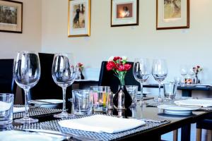 una mesa con copas de vino y un jarrón con flores rojas en Rollestone Manor B&B and Restaurant, en Shrewton