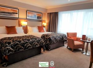 a hotel room with two beds and a table at Clayton Hotel Silver Springs in Cork