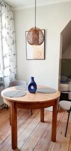 a dining room table with a blue vase on top of it at Apartamenty Loft Rooms - centrum, bezpłatny parking in Ełk