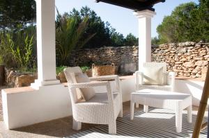 porche con sillas blancas y pared de piedra en Cas Saliners - Parc Natural en La Savina