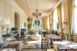 una sala da pranzo con tavoli e lampadario pendente di Villa Parisi Grand Hotel a Castiglioncello