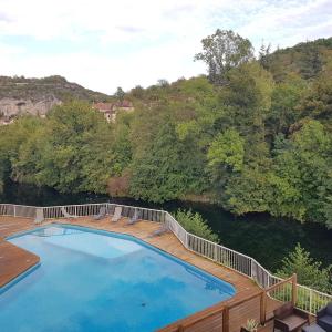 una piscina en una terraza de madera junto a un río en Le Refuge du Cele, en Cabrerets