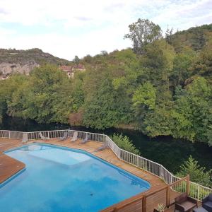 a swimming pool on a wooden deck next to a river at Le Refuge du Cele in Cabrerets