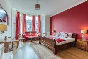 No32 Hotel في إدنبرة: غرفة نوم بجدران حمراء وسرير واريكة