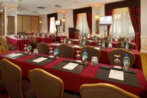 una sala de conferencias con mesas rojas y sillas con botellas. en Warwick New York, en Nueva York