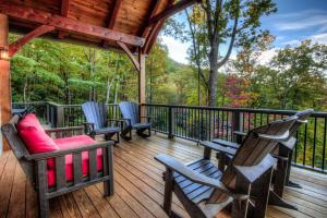 a porch with rocking chairs and a deck with trees at Rustic Timber in Montreat