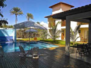 a patio with chairs and an umbrella and a swimming pool at O CAIPIRA NA PRAIA antiga pousada do holandes in Barra Grande
