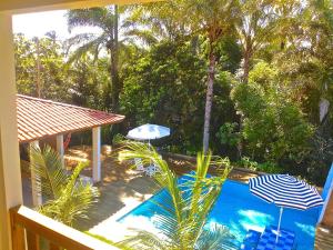 una piscina con 2 sombrillas y palmeras en Pousada do Holandes Bahia, en Barra Grande