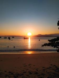 a sunset on the beach with boats in the water at Casa de Praia Picinguaba in Ubatuba