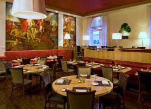 a restaurant with tables and chairs and a large painting on the wall at Warwick New York in New York +28 photos