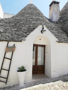 a white building with a wooden door and a roof at Luxury trulli Sabotino in Alberobello +31 photos