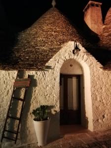 a white building with a door and a plant at Luxury trulli Sabotino in Alberobello