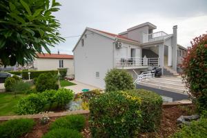 a white house with a yard with bushes at Apartmani IVA in Neum