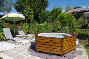 uma banheira de hidromassagem num jardim com cadeiras e um guarda-sol em Maison Elizondoa em Masparraute